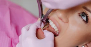 Pembe örtülü ünitte yatan hastanın ağzında pembe eldivenli ellerin pensle çalışması (temsili görsel)